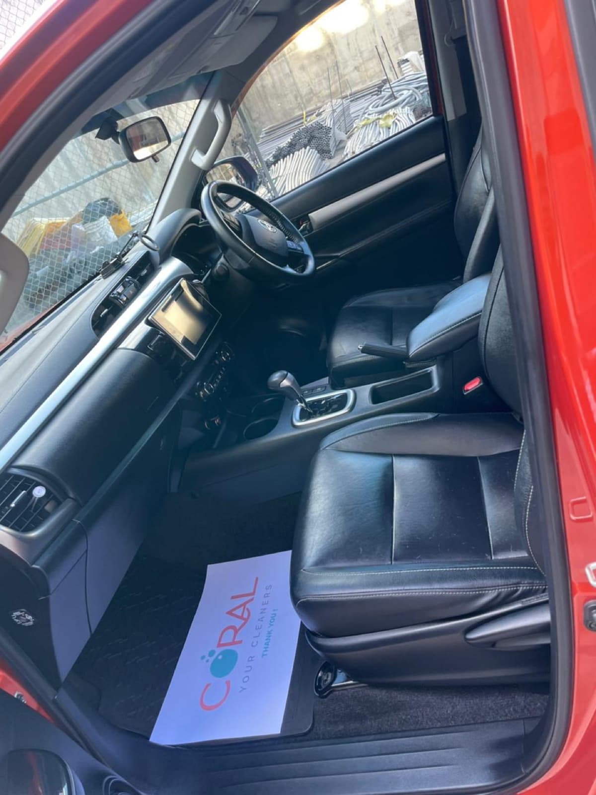 Pickup interior with cleaned leather seats and a Coral Cleaners thank-you sheet